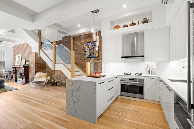 kitchen featuring stainless steel oven, modern cabinets, open floor plan, and wall chimney range hood