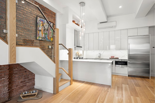 kitchen featuring a sink, stainless steel appliances, modern cabinets, and an AC wall unit