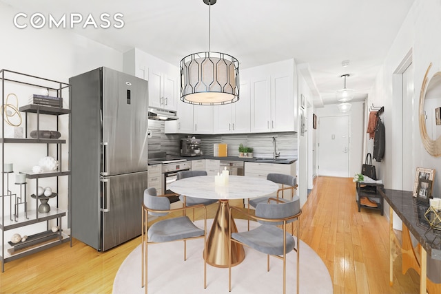 kitchen featuring under cabinet range hood, dark countertops, freestanding refrigerator, and a sink