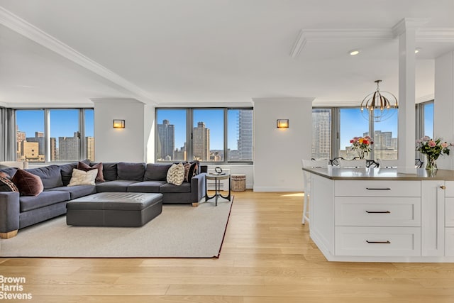 living room with crown molding, a view of city, a notable chandelier, and light wood finished floors