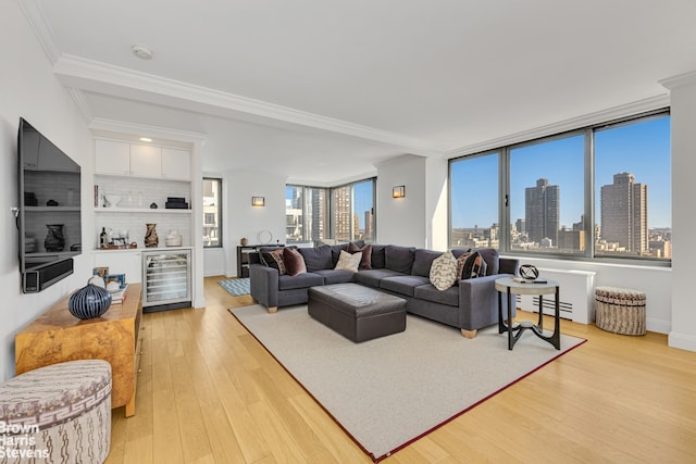 living room featuring a city view, a dry bar, light wood-style floors, and ornamental molding