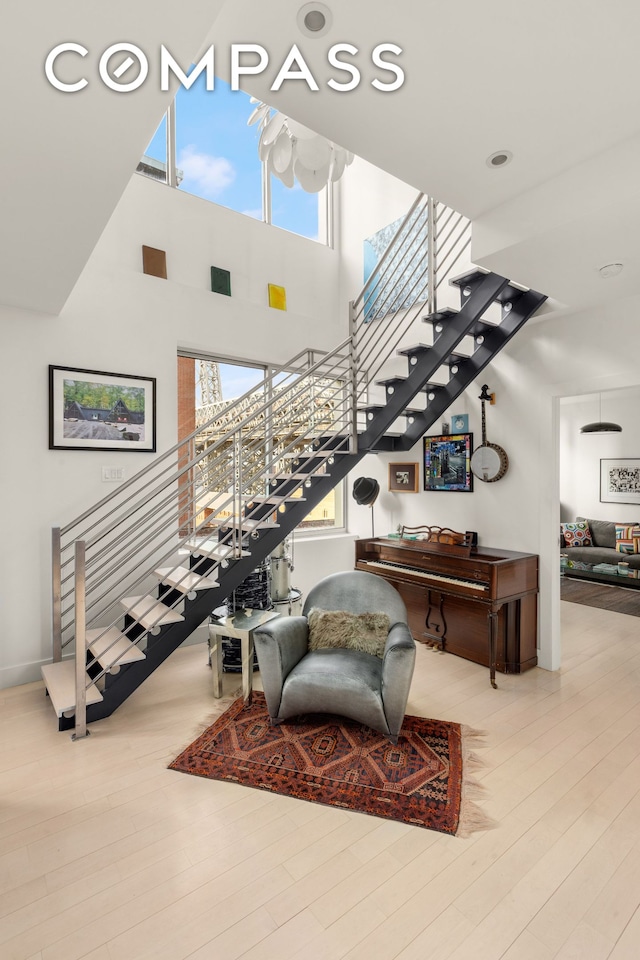 staircase with wood finished floors and a towering ceiling