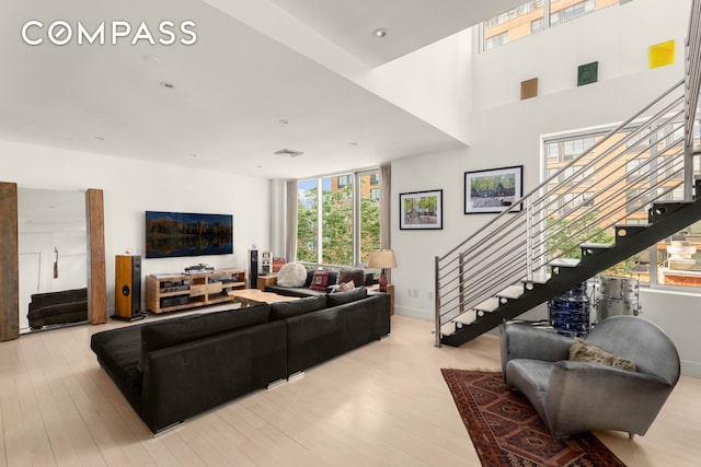 living area featuring light wood-type flooring, visible vents, recessed lighting, stairway, and baseboards