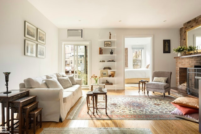 living room featuring plenty of natural light, a brick fireplace, and wood finished floors