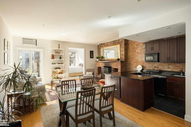 dining space featuring a fireplace, light wood-type flooring, and a wall mounted AC