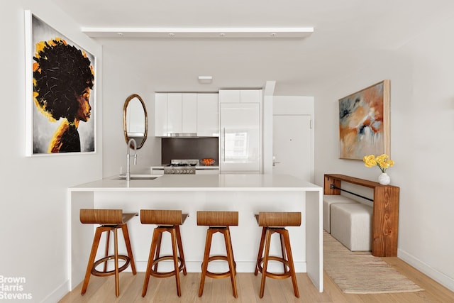 301 W 53rd St Unit 10I, New York City, NY 10019 - kitchen featuring white cabinetry, a breakfast bar area, light wood-style flooring, and light countertops