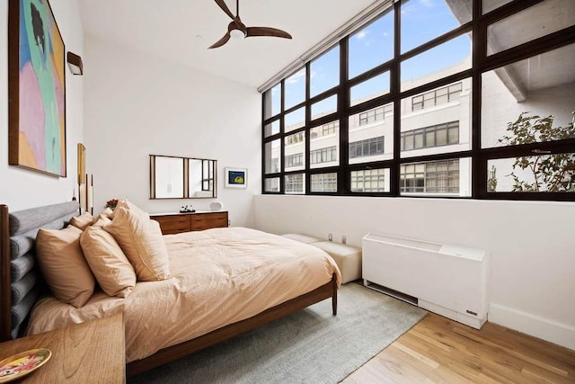 bedroom with a high ceiling, baseboards, and light wood finished floors