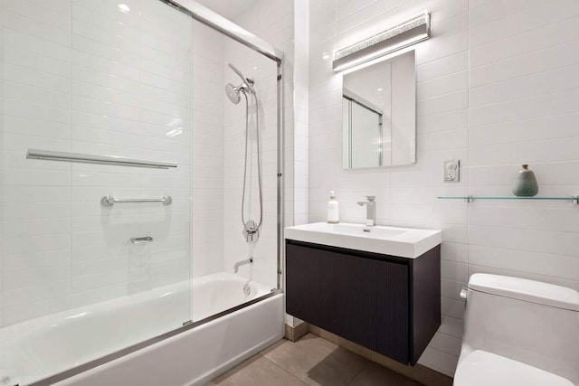 bathroom with vanity, enclosed tub / shower combo, tile patterned floors, toilet, and tile walls