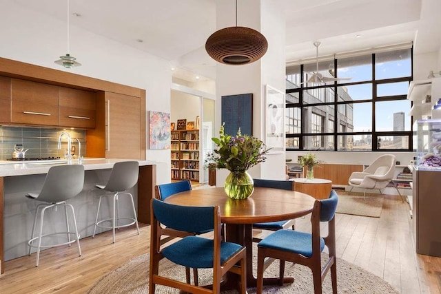 dining room with light wood-style floors and a towering ceiling