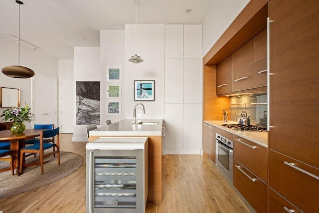 kitchen featuring modern cabinets, beverage cooler, a sink, backsplash, and appliances with stainless steel finishes