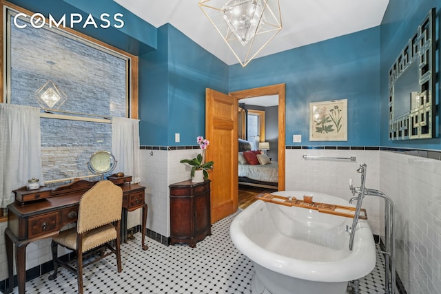 bathroom featuring tile walls, a freestanding tub, and wainscoting