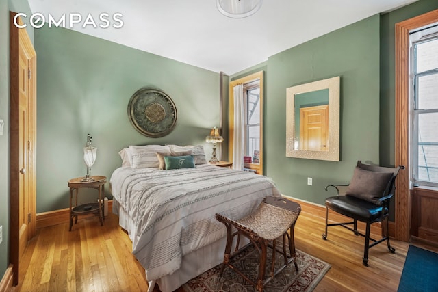 bedroom with multiple windows, baseboards, and wood finished floors