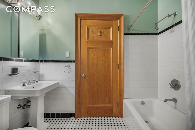 full bathroom featuring a wainscoted wall, shower / bath combination with curtain, tile walls, toilet, and tile patterned floors