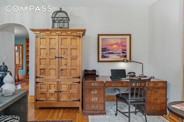 office area featuring arched walkways and wood finished floors