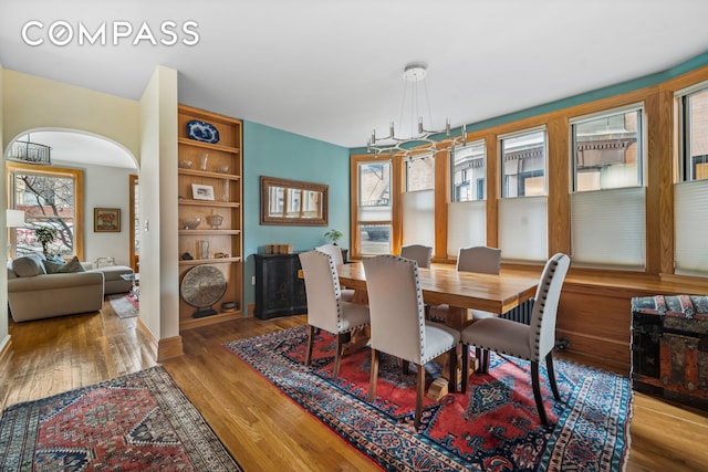 dining space with wood finished floors and arched walkways