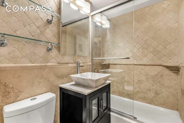 full bath featuring toilet, vanity, and shower / bath combination with glass door