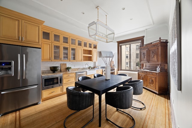 kitchen featuring tasteful backsplash, stainless steel appliances, glass insert cabinets, and light wood-style floors