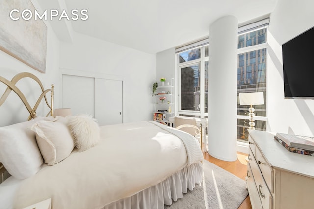 bedroom featuring a closet, floor to ceiling windows, and light wood-type flooring