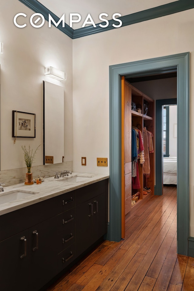 full bath with double vanity, hardwood / wood-style flooring, and a sink