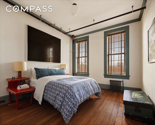 bedroom featuring hardwood / wood-style flooring, radiator heating unit, and baseboards