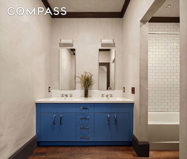 bathroom featuring a sink, wood finished floors, double vanity, and ornamental molding