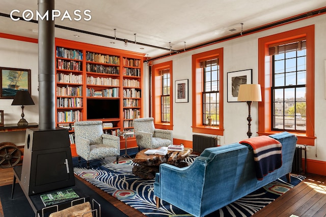 living room with radiator, track lighting, a wood stove, and hardwood / wood-style flooring