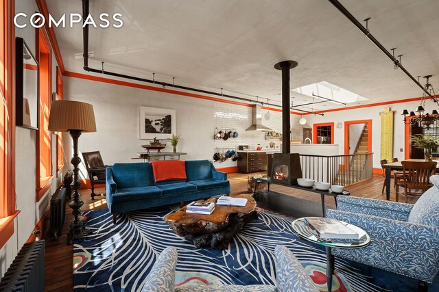 living area featuring radiator, a skylight, a wood stove, and wood finished floors