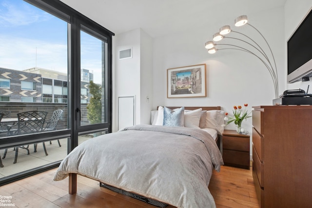 bedroom with a wall of windows, visible vents, and hardwood / wood-style floors