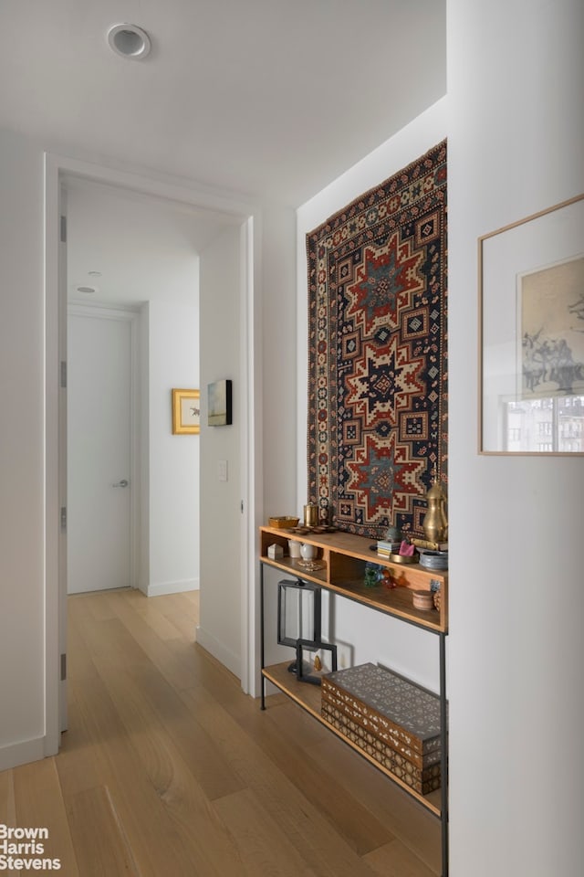 hallway featuring light wood-style flooring and baseboards