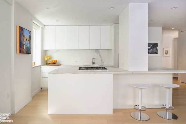 kitchen with stainless steel gas cooktop, white cabinetry, modern cabinets, and light wood-type flooring