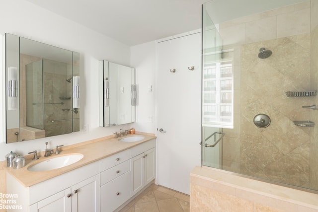 bathroom with a sink, a stall shower, double vanity, and tile patterned floors