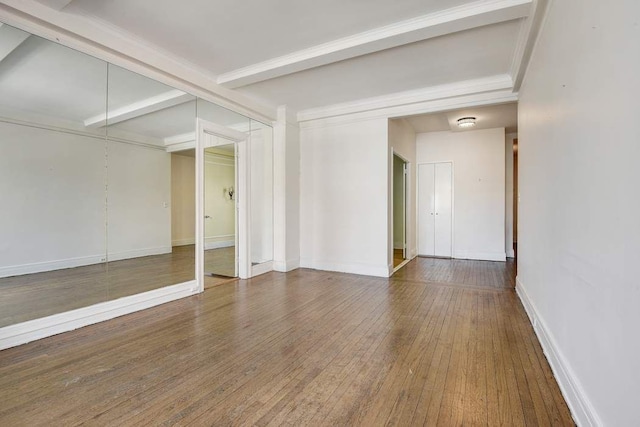 unfurnished room featuring baseboards, beam ceiling, crown molding, and hardwood / wood-style flooring