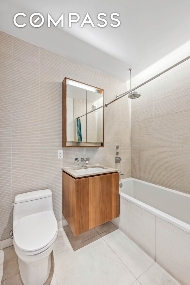 full bath featuring tile patterned flooring, tile walls, shower / washtub combination, toilet, and vanity