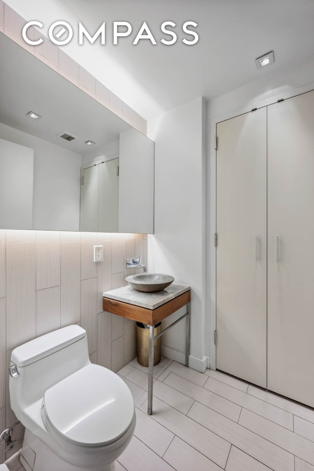 bathroom featuring a shower with door, toilet, and a sink