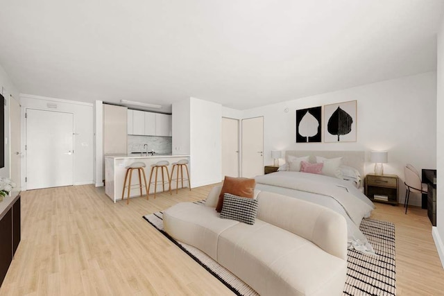 bedroom with a sink and light wood-style floors