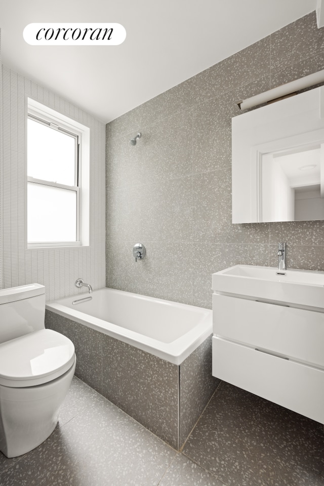 full bath with vanity, tiled shower / bath combo, toilet, and tile walls