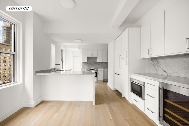 kitchen featuring light wood finished floors, visible vents, beverage cooler, white cabinets, and range