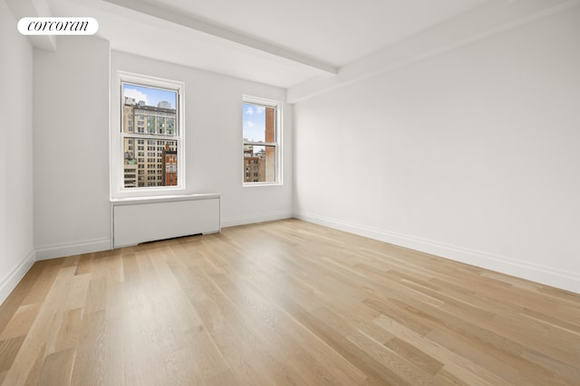 empty room featuring visible vents, baseboards, light wood-style floors, and beam ceiling