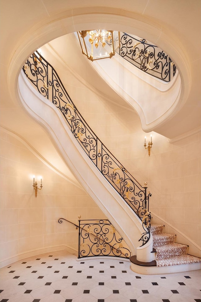 stairs with tile walls, a towering ceiling, and a chandelier