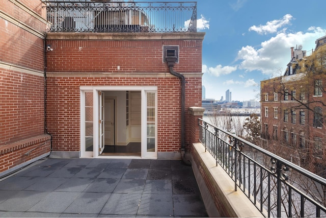 exterior space featuring brick siding, a balcony, and a view of city