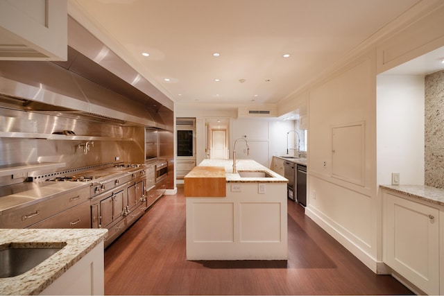 kitchen with a kitchen island with sink, backsplash, ornamental molding, and a sink