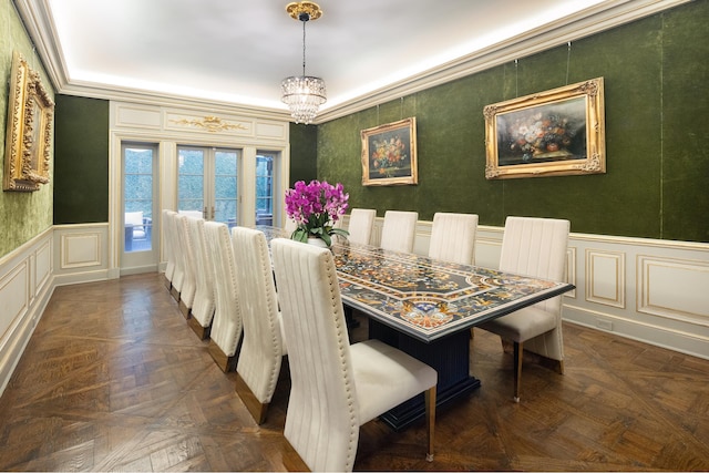 dining area with a wainscoted wall, french doors, an inviting chandelier, crown molding, and a decorative wall