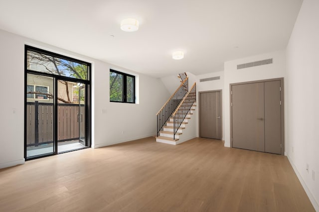 interior space featuring stairs, light wood-style floors, visible vents, and baseboards