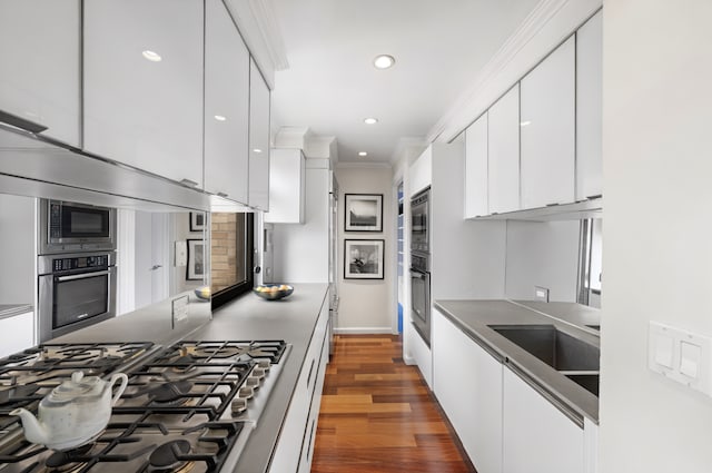 10 W 66th St Unit 27F, New York City, NY 10023 - kitchen with stainless steel appliances, modern cabinets, white cabinetry, dark wood-type flooring, and crown molding