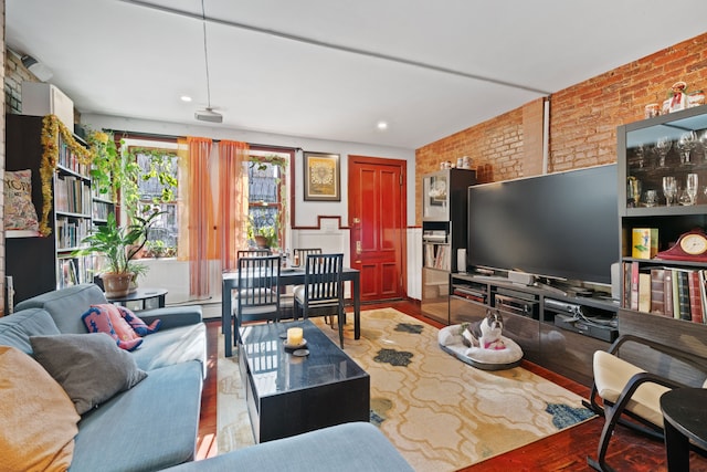 living room featuring wood finished floors and brick wall