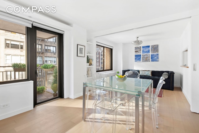 dining space with wood finished floors, a healthy amount of sunlight, and baseboards