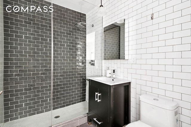 full bathroom featuring toilet, tile walls, vanity, and a tile shower