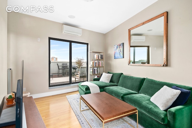 living area with plenty of natural light, wood finished floors, and a wall mounted air conditioner