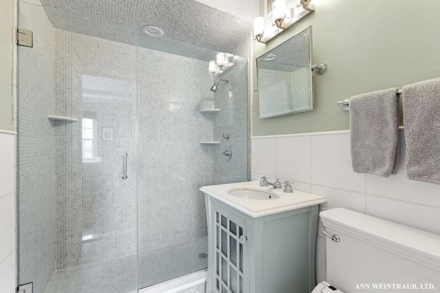 full bath featuring vanity, tile walls, toilet, and a stall shower