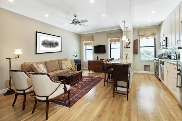 living room with crown molding, recessed lighting, baseboards, and light wood-type flooring